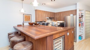 A modern kitchen with wooden cabinets, stainless steel appliances, and a central island with stools. - Cozy Couple's Retreat in Downtown Telluride (Telluride)