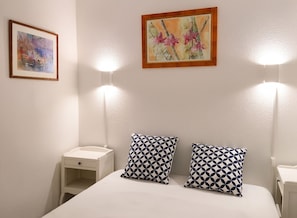 A bedroom with a bed, two bedside tables, and two wall-mounted lamps.