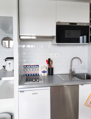 A compact kitchen with a microwave, toaster, and a sink.