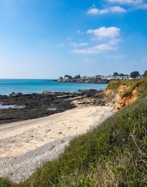 A coastal landscape with a sandy beach, rocky shoreline, and a row of houses in the background. - Homerez - Flat in Guérande (Guérande)