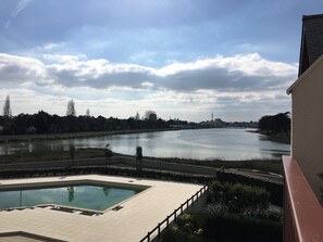 A view of a river with a swimming pool in the foreground and a building on the right.