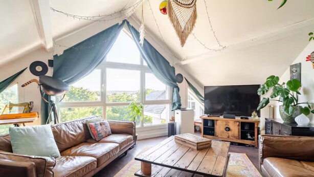 A cozy living room with a leather sofa, a wooden coffee table, and a large TV.