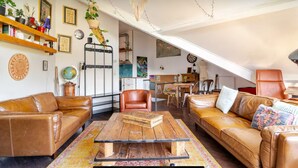 A spacious living room with leather sofas, a wooden coffee table, and a kitchen in the background.