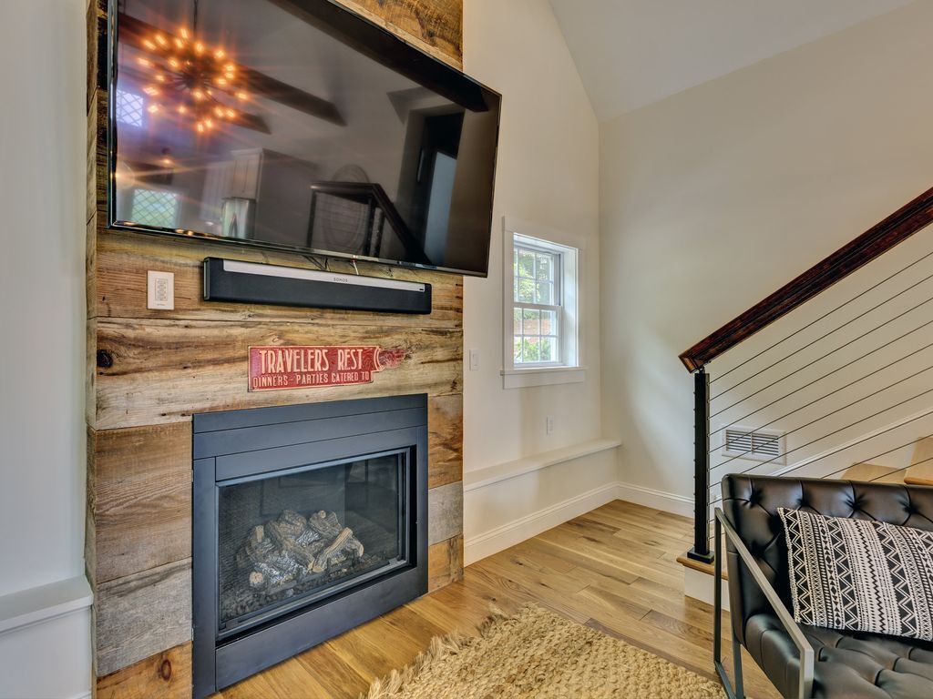 A modern living room with a fireplace, a mounted TV, and a cozy seating area.