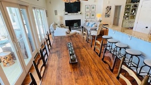 Une salle à manger spacieuse avec une longue table en bois, de nombreuses chaises et un lustre.