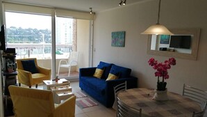 Un salon comprenant un canapé, des fauteuils, une table à manger et un téléviseur.