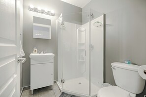 Ein modernes Badezimmer mit einer Duschkabine, einem weißen Waschbecken und einer Toilette.