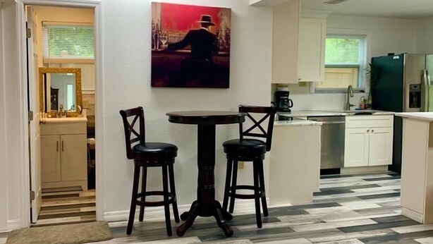 Un coin repas avec une table et deux chaises, une cuisine en arrière-plan et un sol à motifs.