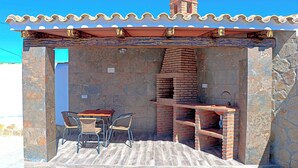 Eine Terrasse im Freien mit einem Backofen aus Ziegeln, einem Tisch und zwei Stühlen.