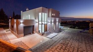A modern house with a fireplace, large windows, and a patio area. - Villa Domenica with Heated Pool (Solin)