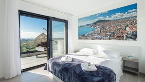 A bedroom with a bed, a hanging chair, and a large window with a cityscape view. - Villa Domenica with Heated Pool (Solin)