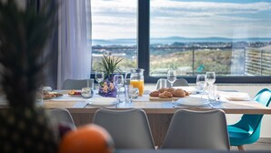 A dining table set with plates, glasses, and a pitcher of orange juice, overlooking a scenic view. - Villa Domenica with Heated Pool (Solin)