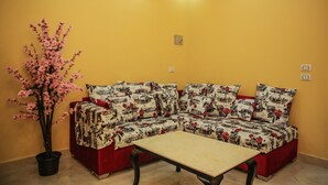 A living room with a sectional sofa, a coffee table, and a potted plant. - Queen Pyramids View Inn (Giza)
