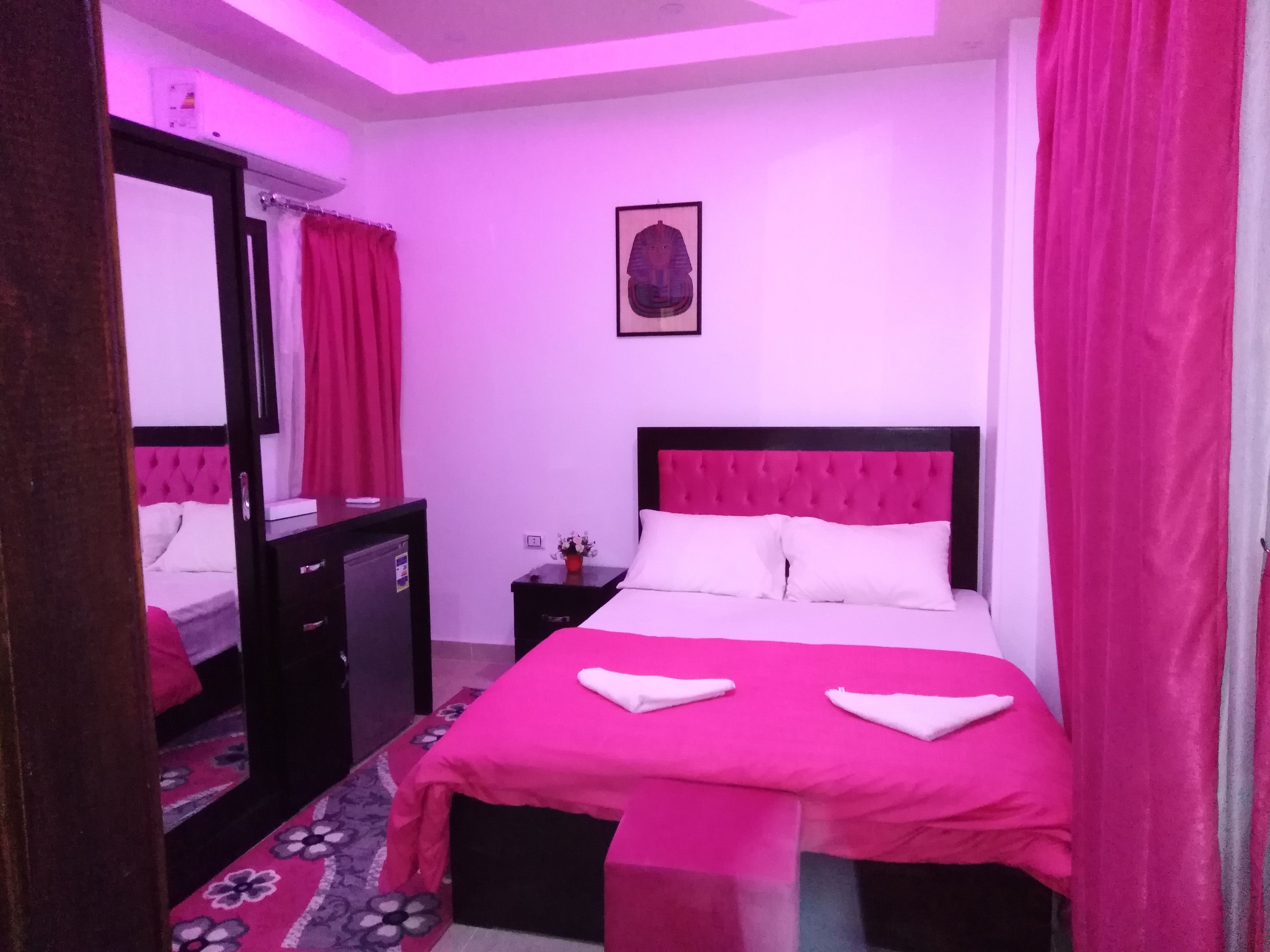 A hotel room with a large bed, a dresser, a mirror, and a small table with a vase.