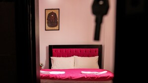 A bedroom with a red bedspread, white pillows, and a red floral rug. - Queen Pyramids View Inn (Giza)