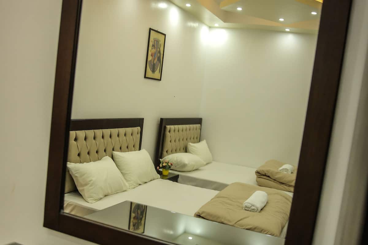 A hotel room with a large mirror, two beds, and a small table.