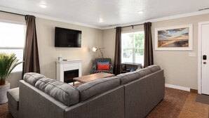 A living room with a gray sectional sofa, a fireplace, a flat-screen TV, and a painting on the wall. - The Lake View: Family and business travel (Lehi)