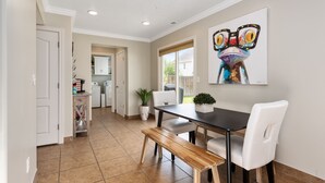 A dining area with a table, chairs, and a bench. There is a kitchen in the background with cabinets and appliances. - The Lake View: Family and business travel (Lehi)