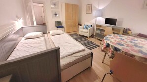 Une chambre d’hôtel avec deux lits, un bureau, une chaise, une télévision et une lampe.