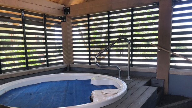 An outdoor hot tub with a blue mat, surrounded by wooden decking and metal railings. - Cozy, updated 2 Bedroom / 2 Bathroom condo (Steamboat Springs)