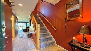 Una escalera con barandillas de madera, peldaños alfombrados y una pared roja.