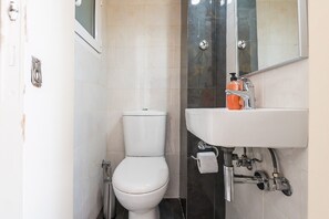 Ein kleines Badezimmer mit Toilette, Waschbecken mit Spiegel und einem Handtuch an der Wand.