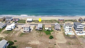 An aerial view of a coastal residential area with houses, a beach, and the ocean. - Classic, semi ocean front OBX cottage steps away from the beach. (Kitty Hawk)