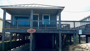 A wooden pier leading to a house with a balcony, a resident parking sign, and a no parking sign. - Classic, semi ocean front OBX cottage steps away from the beach. (Kitty Hawk)
