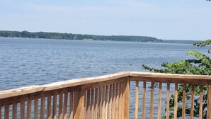 A wooden deck with a railing overlooking a calm body of water.