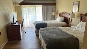 Habitación de hotel con dos camas, un escritorio y una silla.
