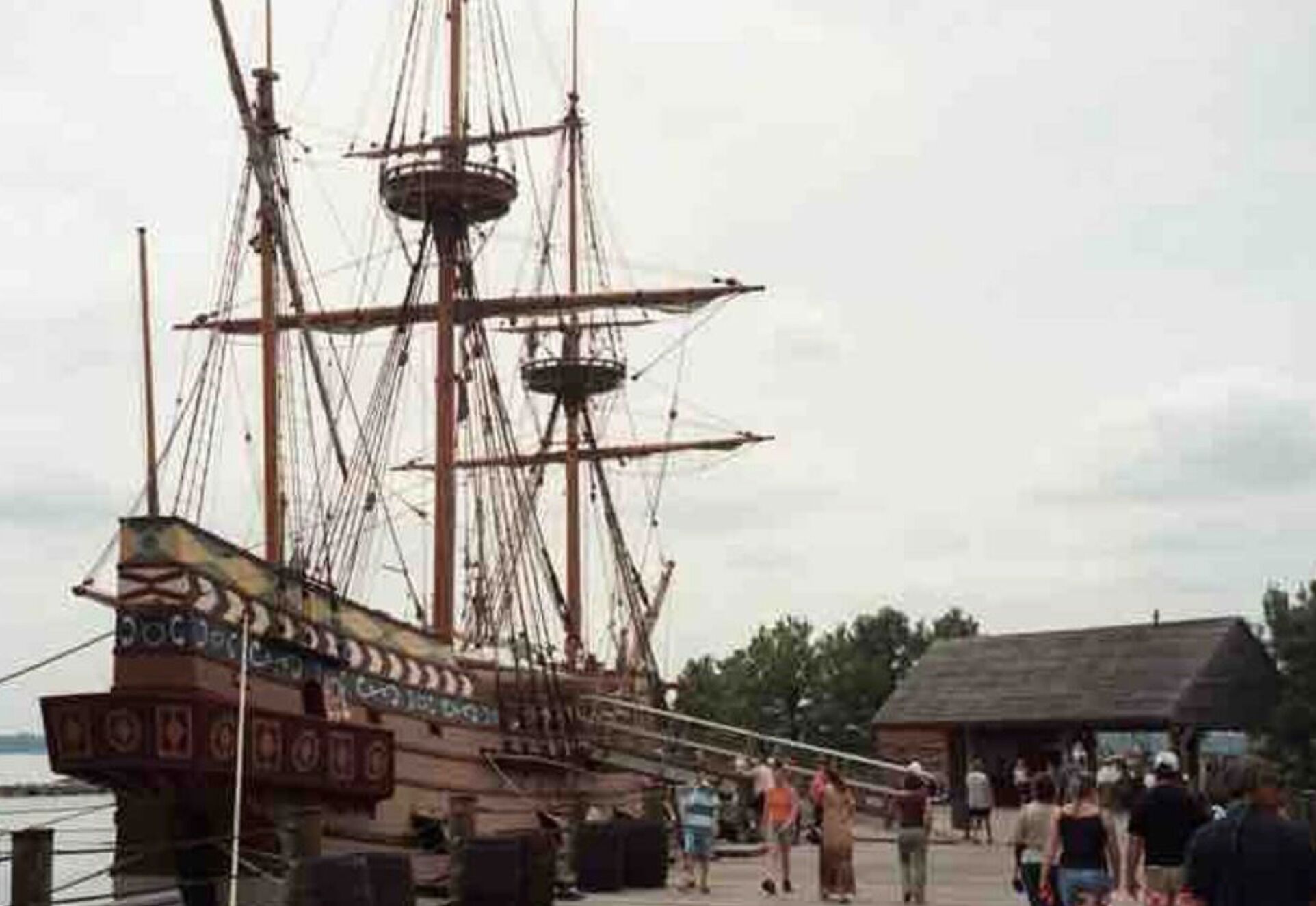 Un grand voilier était amarré à un quai, et des gens se promenaient aux alentours.