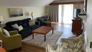 Un salón amplio con un conjunto de sofás, una mesa de centro y un televisor.