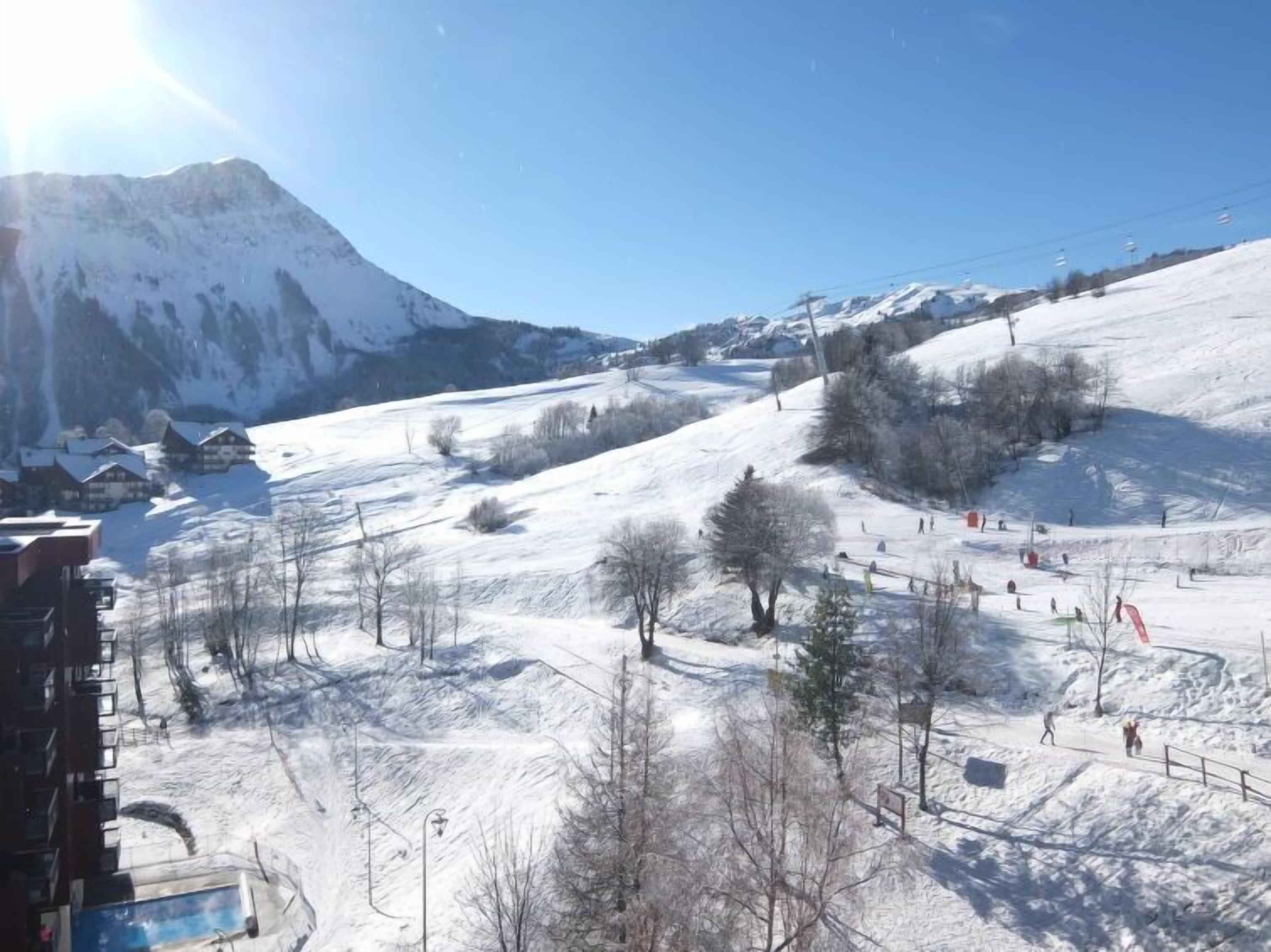 Ein mit Schnee bedeckter Ski-Hang mit Skilift, Gebäuden und Bäumen.