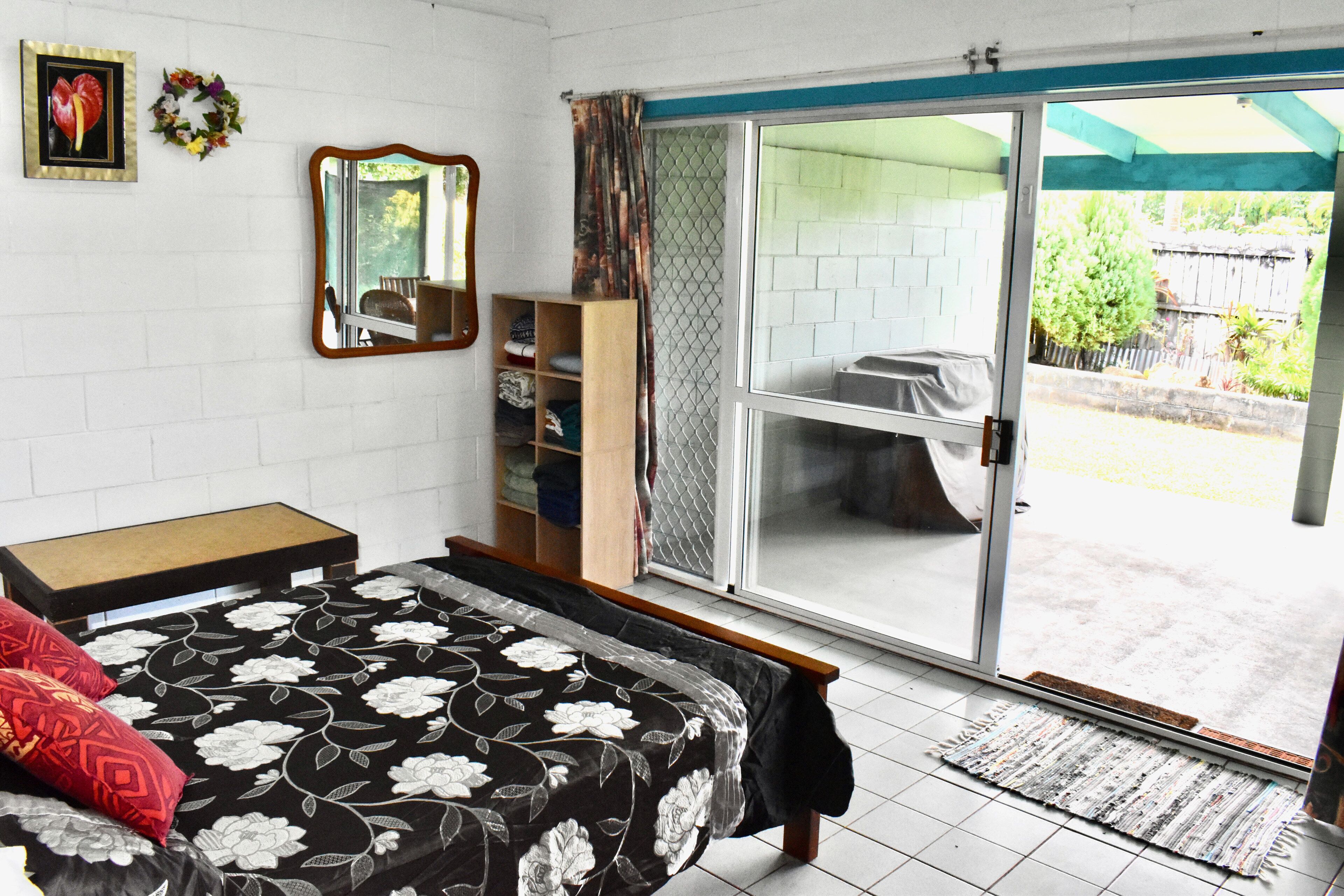 Une chambre à coucher comprenant un lit, une armoire, un miroir et une porte-fenêtre coulissante donnant sur un balcon.