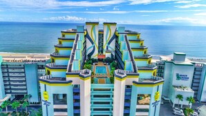 Un hotel con piscina central, varios balcones y vista al océano.