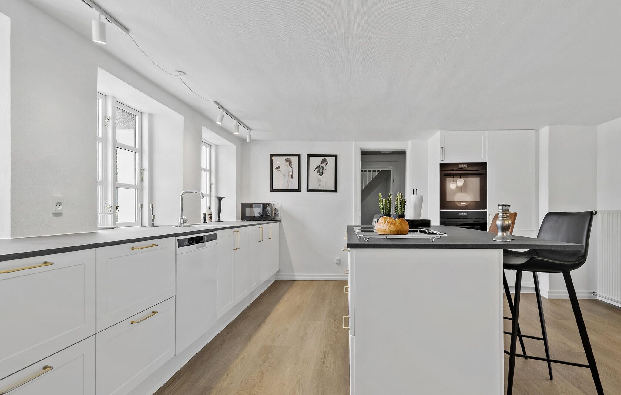 A modern kitchen with white cabinetry, a central island, and a black bar stool.