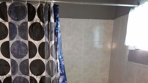 A bathroom with a shower curtain featuring a circular pattern, a bathtub, a sink, and a window. - Laura's Place (Port Antonio)