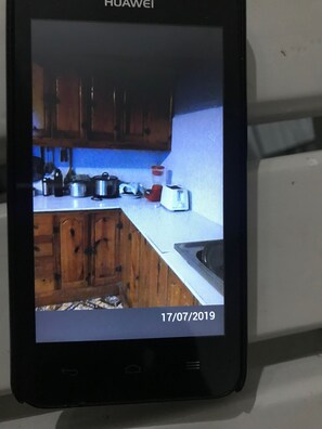 A Huawei smartphone displaying a kitchen with wooden cabinets, a white countertop, and various kitchen items.