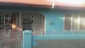 A building with barred windows and a metal gate, suggesting security measures. - Laura's Place (Port Antonio)