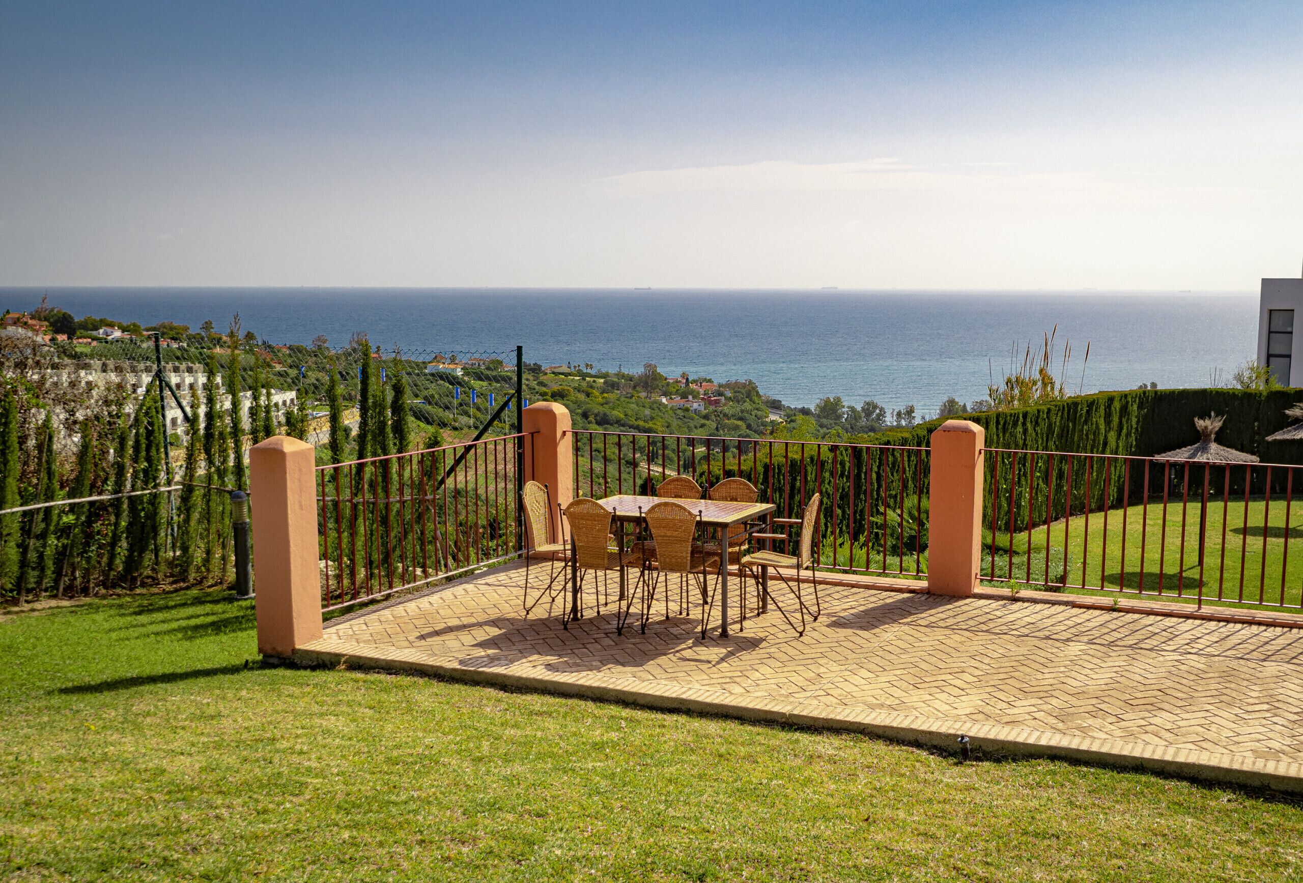 A patio with a table and chairs overlooking a coastal view.