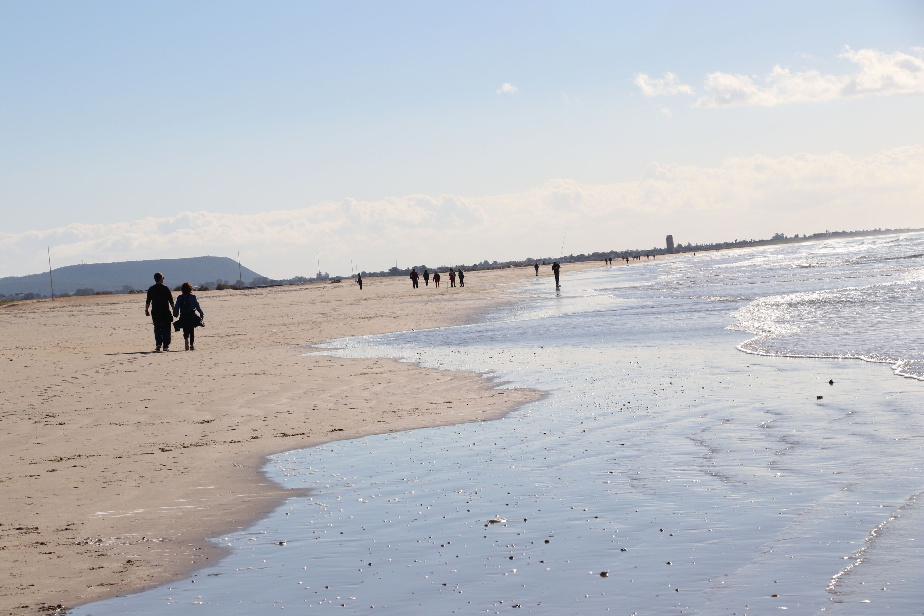 Ein Strand mit Menschen, die am Ufer entlanggehen.