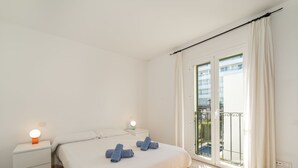 Une chambre à coucher avec un lit, des tables de chevet, une lampe et une vue sur un balcon.