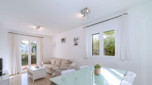 Un salon moderne avec une table à manger en verre, un canapé blanc et un meuble pour la télévision.