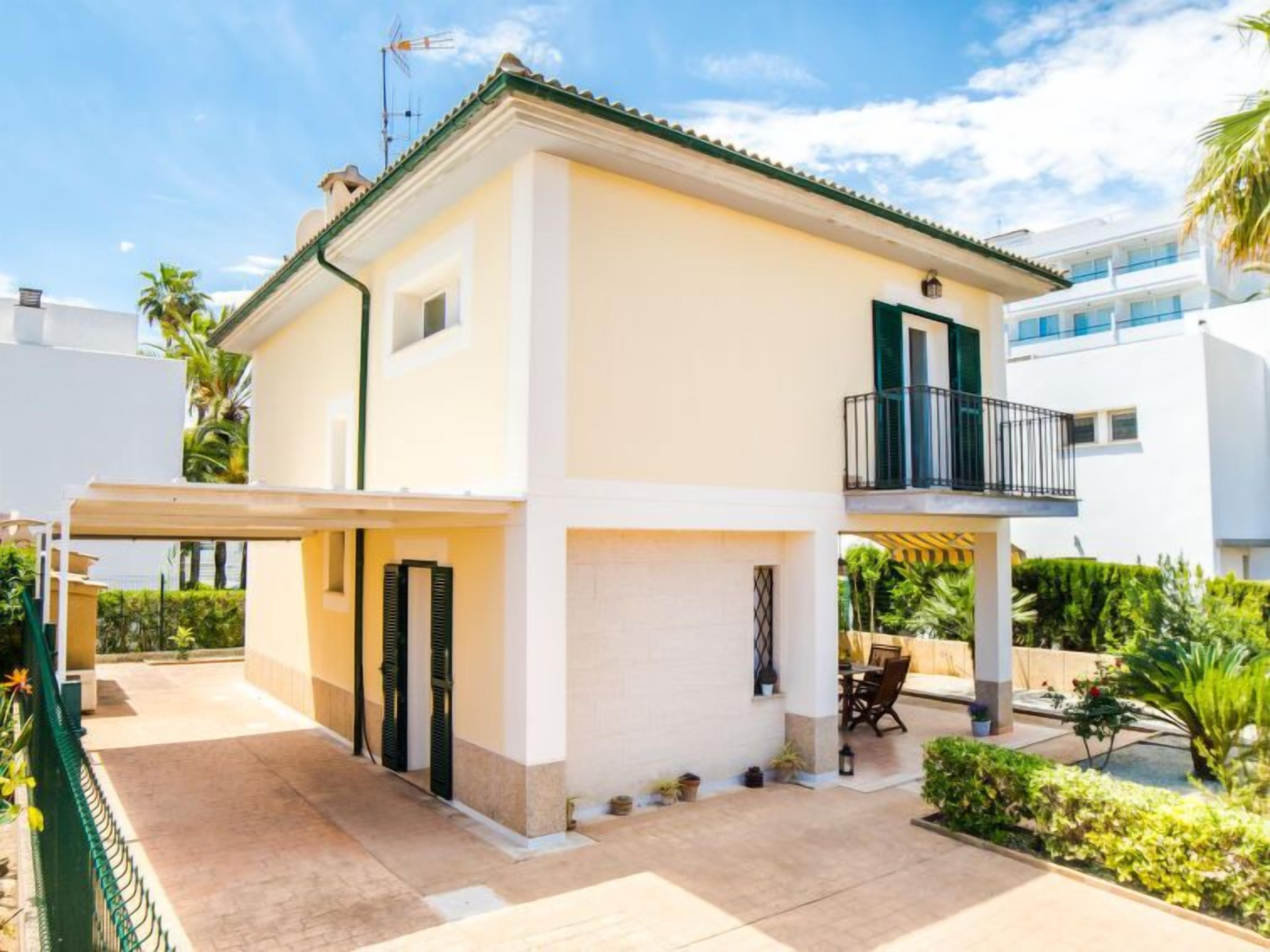 Une maison à deux étages dotée d’un balcon, d’une terrasse couverte et d’un jardin.