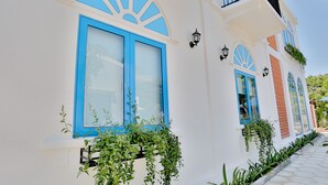 A white building with blue-framed windows and a balcony.