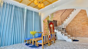 A room with a staircase, a wooden bench, a table, and a vase with flowers.