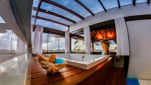 Una habitación soleada con suelo de madera, un ventanal grande y una bañera.