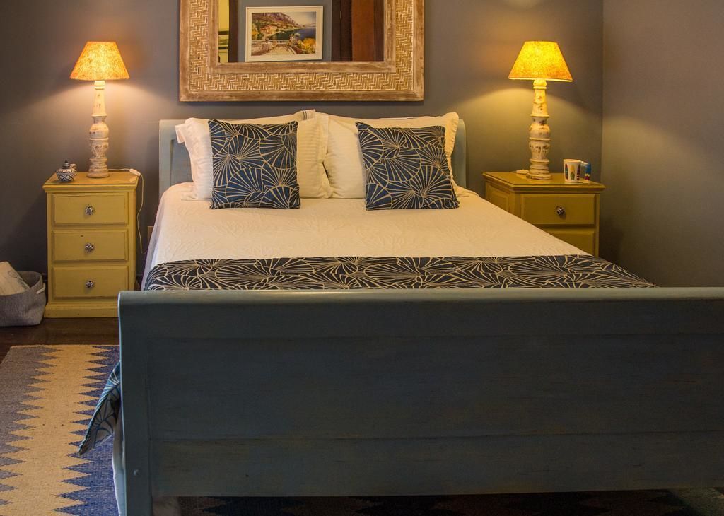 A neatly made bed with patterned pillows, two bedside lamps, and a framed picture on the wall.