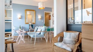 Una sala de estar moderna con una pared azul, una silla de mimbre, un sofá blanco y un comedor con mesa y sillas.