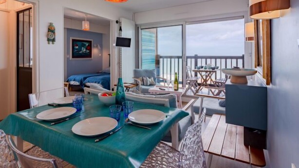 Una habitación moderna con comedor, cama y balcón con vistas.